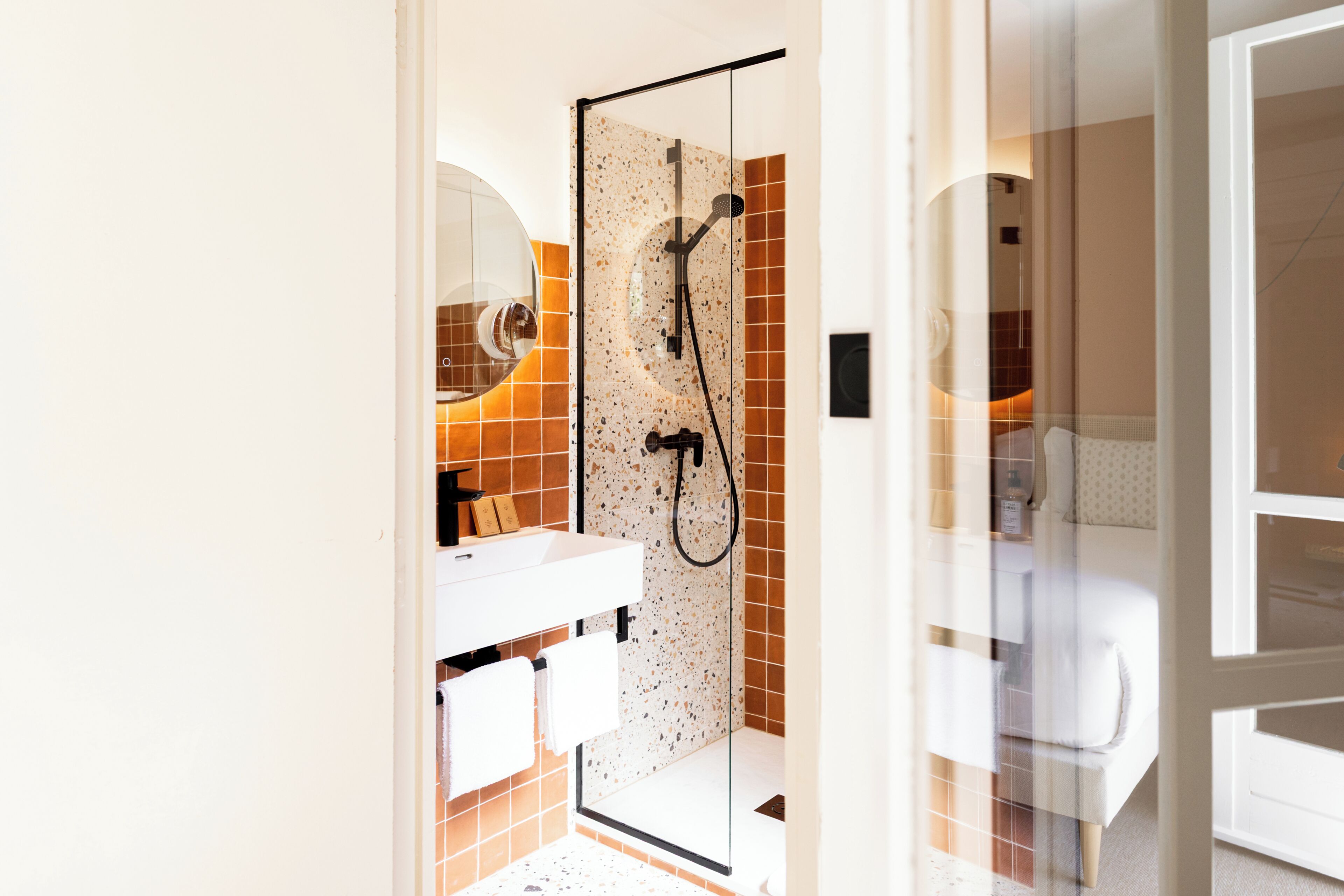 Un baño con cabina de ducha de vidrio, un lavabo blanco y un espejo.