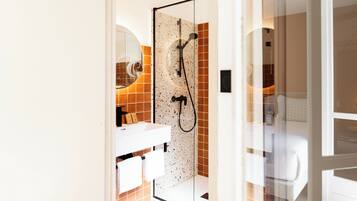 Un baño con cabina de ducha de vidrio, un lavabo blanco y un espejo.