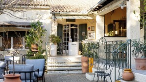 A courtyard with outdoor seating, a reception desk, and a staircase leading to the entrance. - La Garrigue (Venasque)