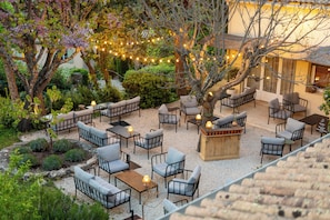 An outdoor seating area with multiple tables and chairs, surrounded by trees and plants.