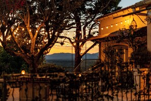 A tree with string lights, a staircase, and a view of mountains.