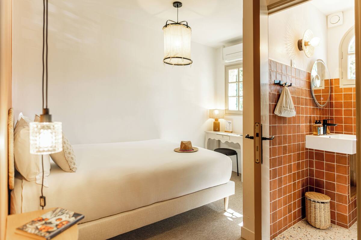 A bedroom with a bed, bedside lamp, and a small table with a magazine.