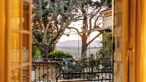 An outdoor seating area with chairs and tables, a tree, and a view of the sea. - La Garrigue (Venasque)