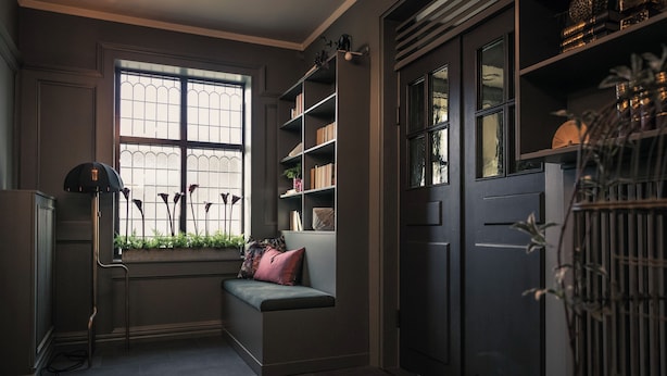 A cozy reading nook with a cushioned bench, a bookshelf, and a window with a view. - Hotel Ranten (Falkoping)