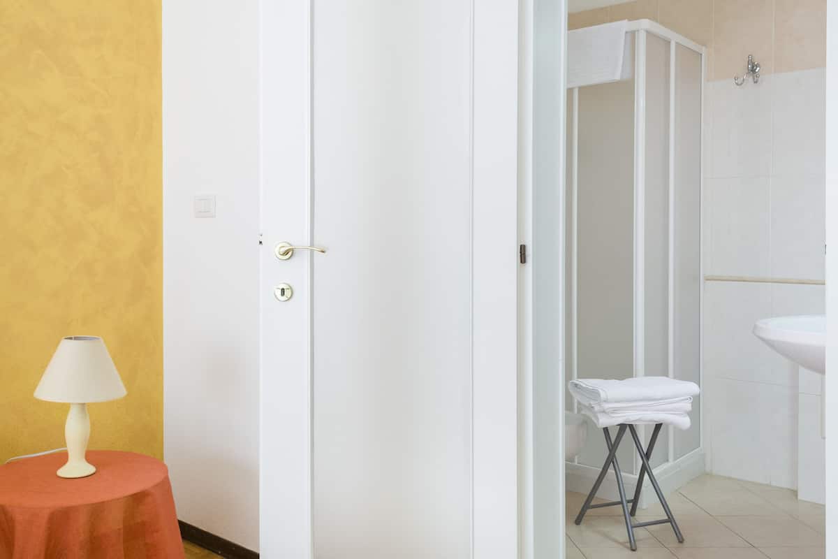 Een badkamer met een douche, wastafel en handdoekrek.