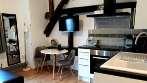 A modern kitchen with a black countertop, white cabinets, and a built-in oven. There is a dining area with a round table and two chairs.