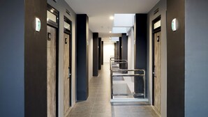 Un corredor moderno de hotel con una escalera central, puertas numeradas 46 y 47, y un letrero que dice "D'Paragon".