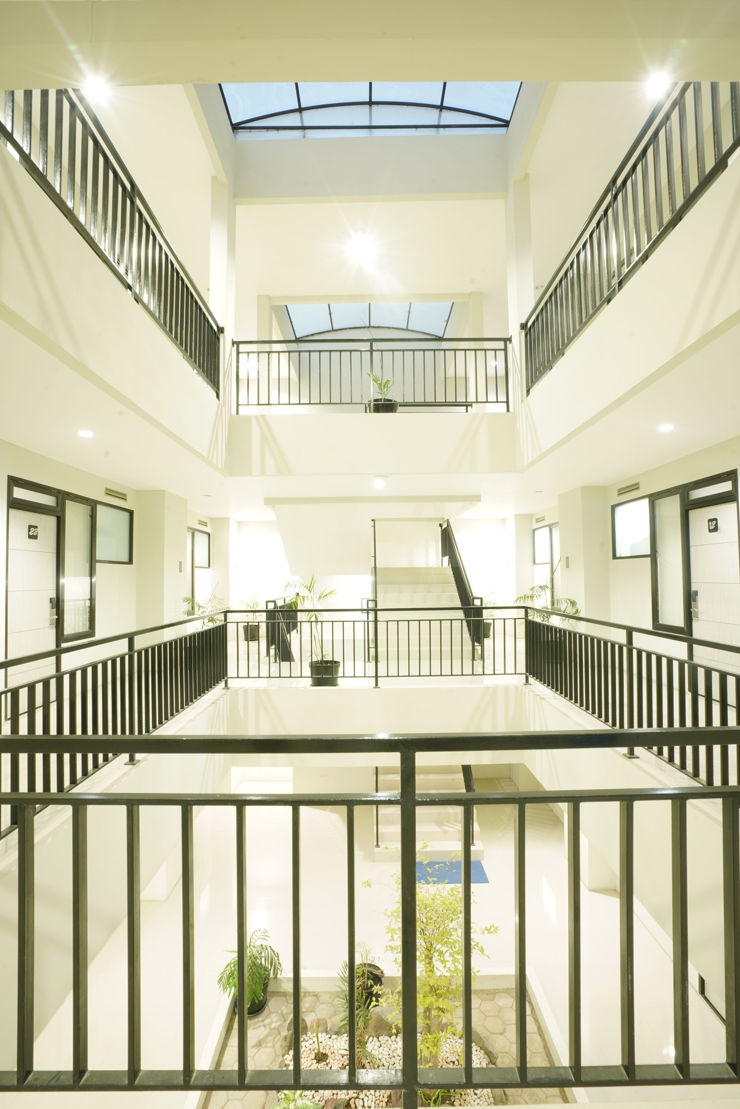 A multi-level atrium with glass ceilings, black railings, and potted plants.
