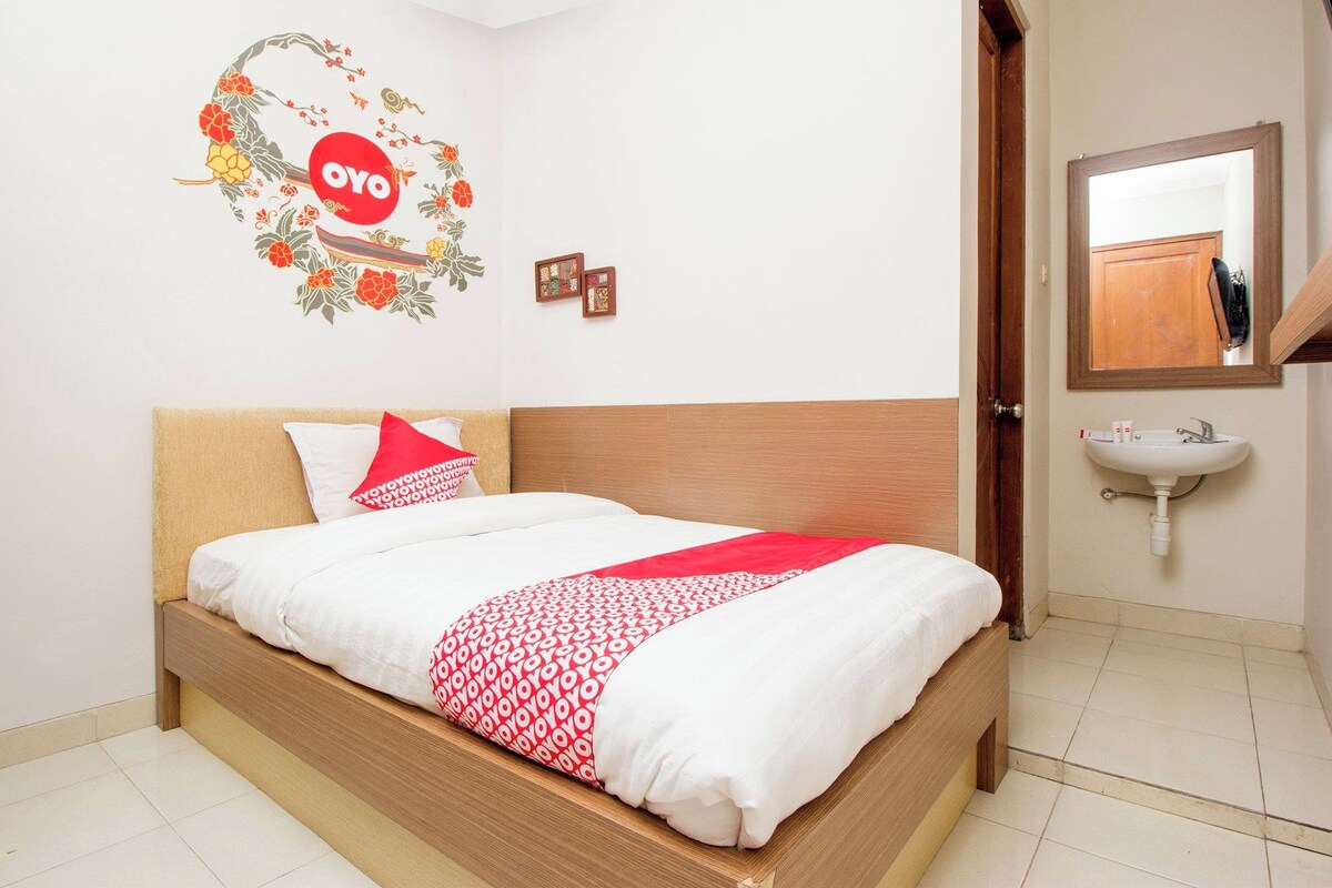 A hotel room with a bed, a wall decoration, a sink, and a mirror.