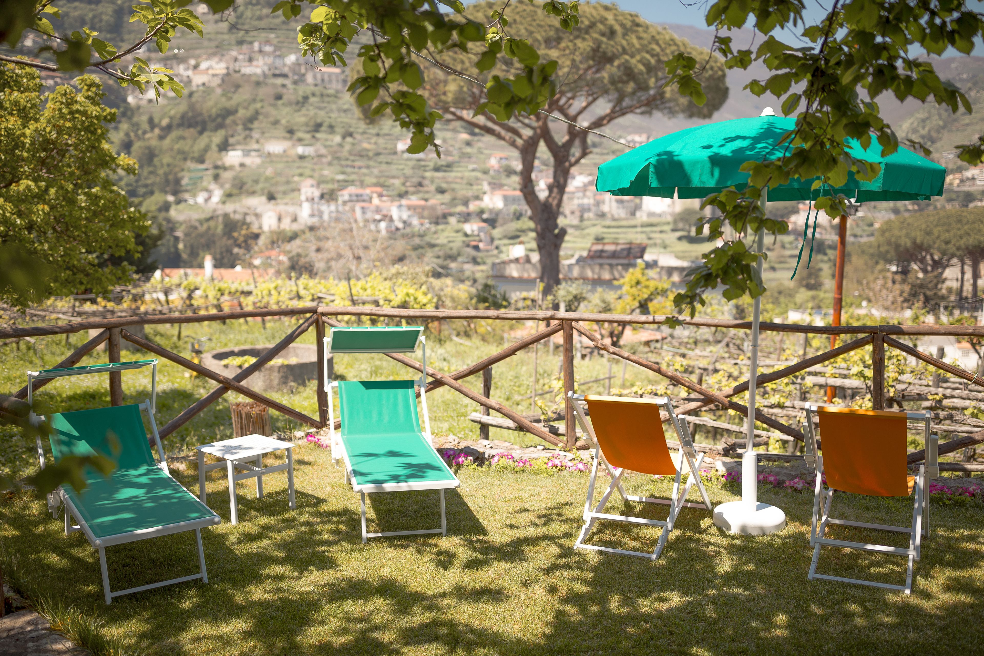 A terrace with outdoor seating and a view of a hillside village.