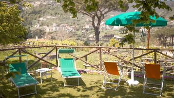 A terrace with outdoor seating and a view of a hillside village.