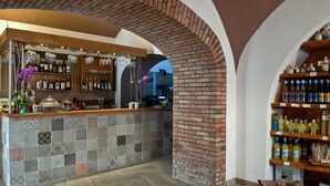 A bar area with a tiled counter, shelves with bottles, and hanging lights. - Mimì B&B (Ravello)
