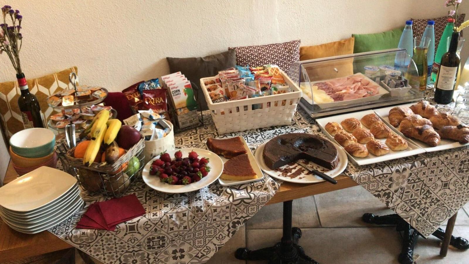A buffet table with various food items, including fruits, pastries, and a chocolate cake.