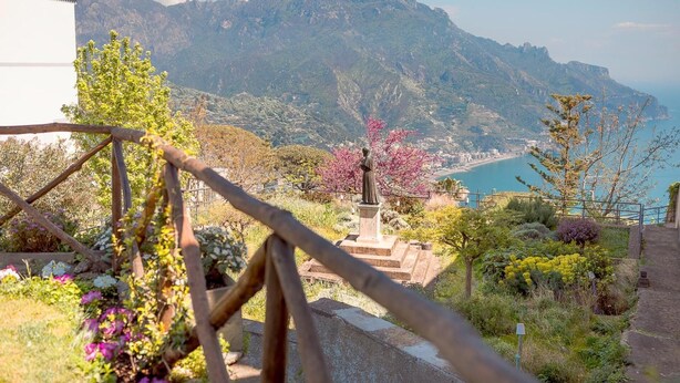 A scenic view of a mountainous landscape with a statue in the foreground, overlooking a coastal area. - Mimì B&B (Ravello)
