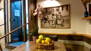 A dining area with a wooden table, a basket of lemons, a potted plant, and a vintage photograph on the wall. - Mimì B&B (Ravello)
