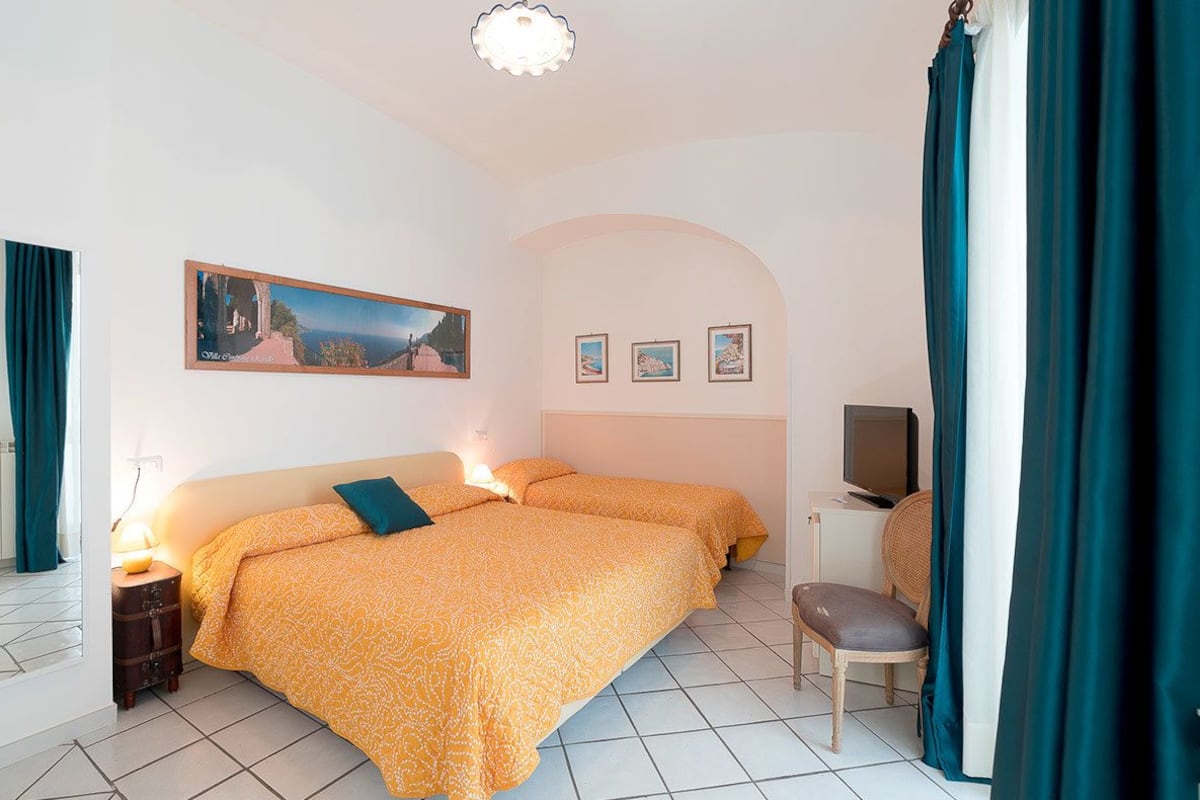 A hotel room with two beds, a television, and a small desk.