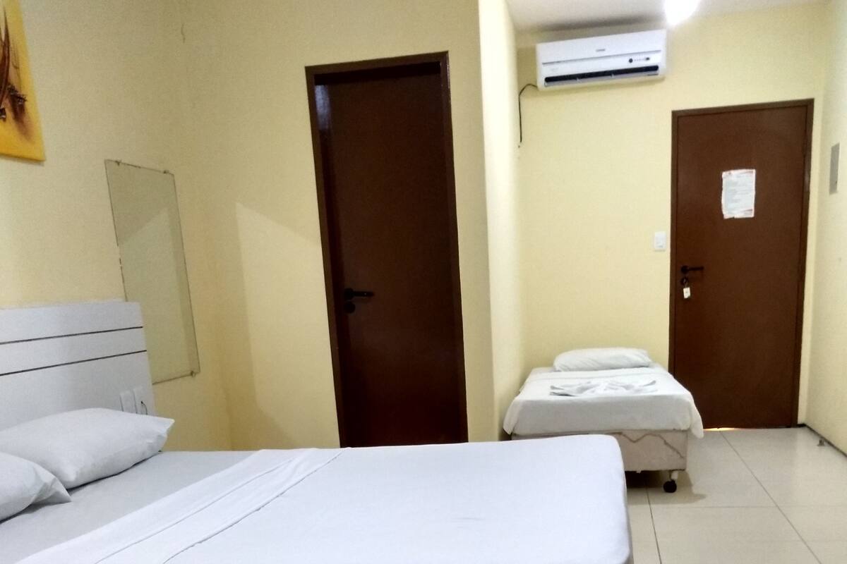 A hotel room with two beds, a door, and an air conditioning unit.