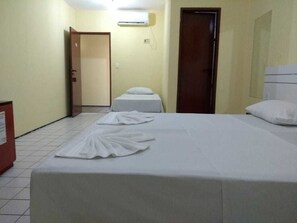 Una habitación de hotel con cama, mesita de noche, armario y puerta.
