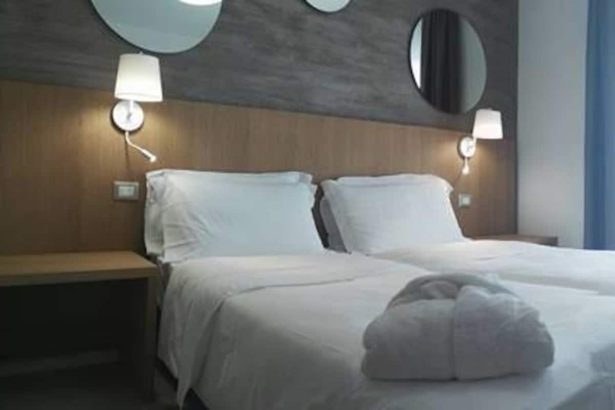 A hotel room with two beds, a desk, and a chair.