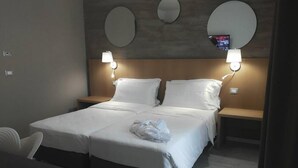 Una camera d'albergo con un letto grande, due comodini e tre specchi a muro.