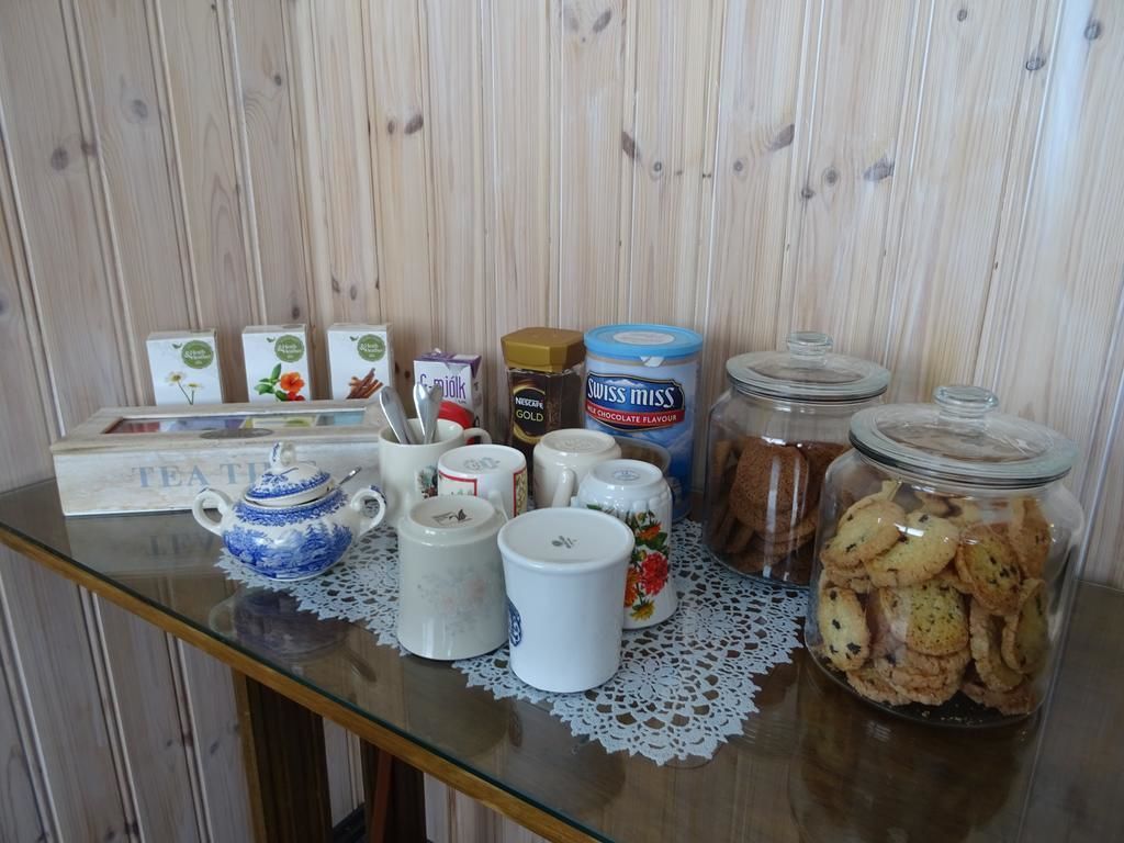 Una mesa con varios utensilios de cocina, como una tetera, tazas, frascos de galletas y una caja con la etiqueta 'TEATIL'.