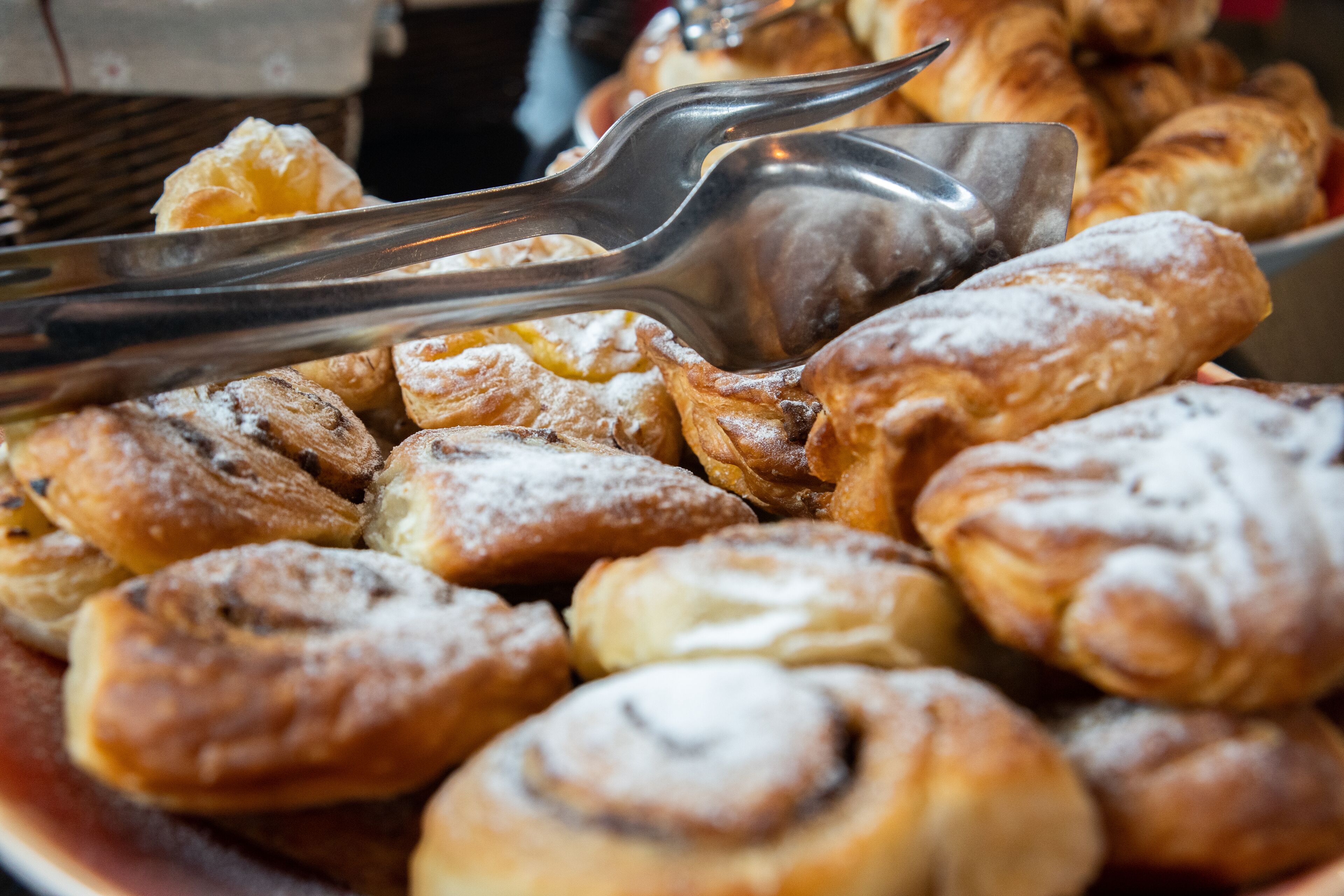 Een selectie gebak, waaronder croissants en kaneelbroodjes, op een bord.