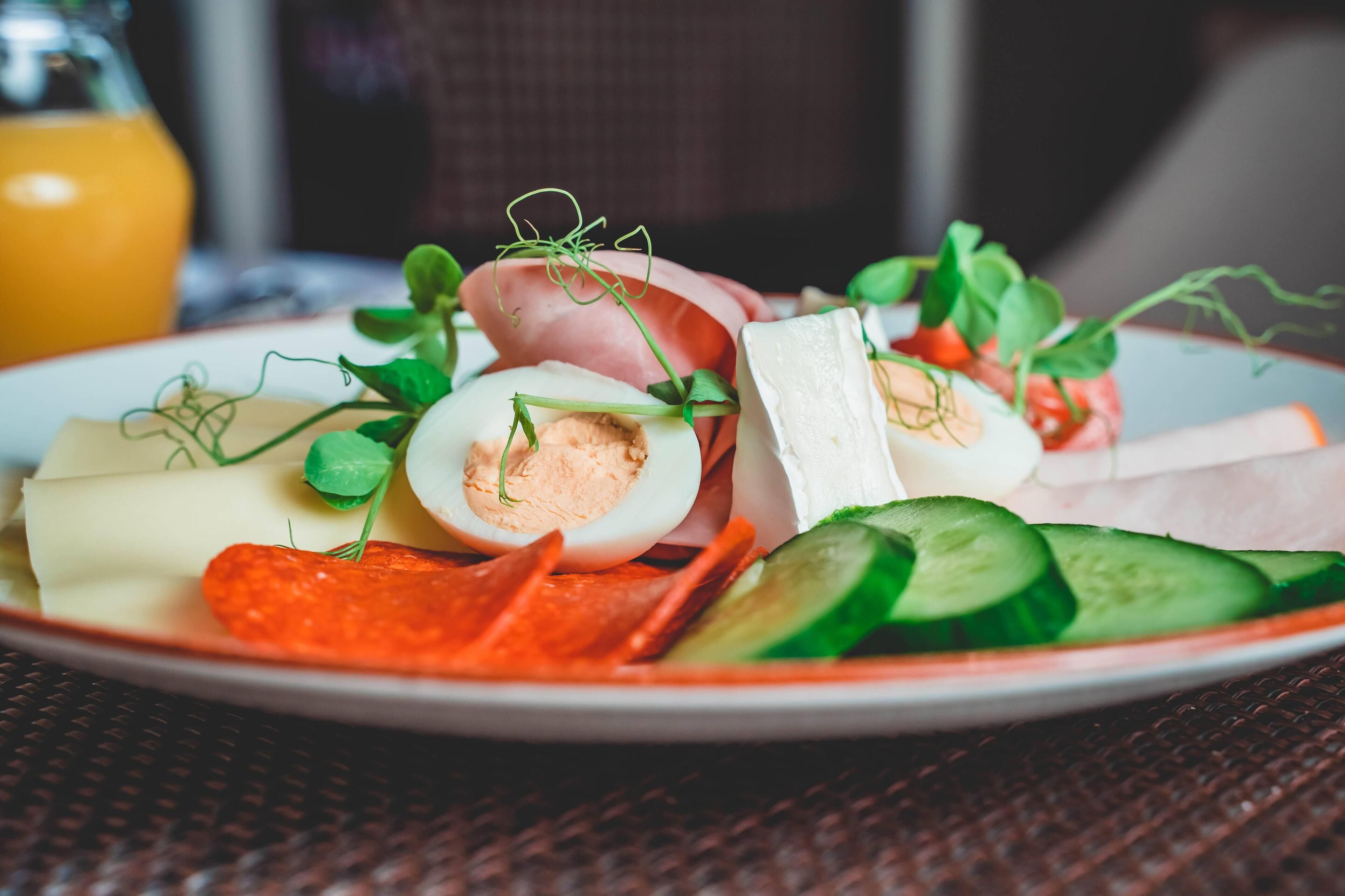 A plate of food with sliced cucumbers, carrots, and a boiled egg.