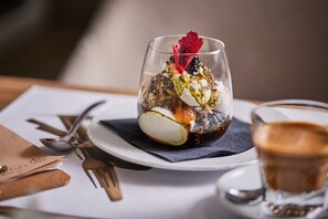 A dessert in a glass on a white plate with a spoon and fork beside it. - The Hotel Unforgettable - Hotel Tiliana by Homoky Hotels & Spa (Budapest)