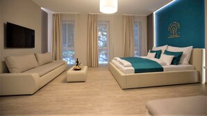 A modern hotel room with a large bed, a sofa, and a flat-screen TV. - The Hotel Unforgettable - Hotel Tiliana by Homoky Hotels & Spa (Budapest)