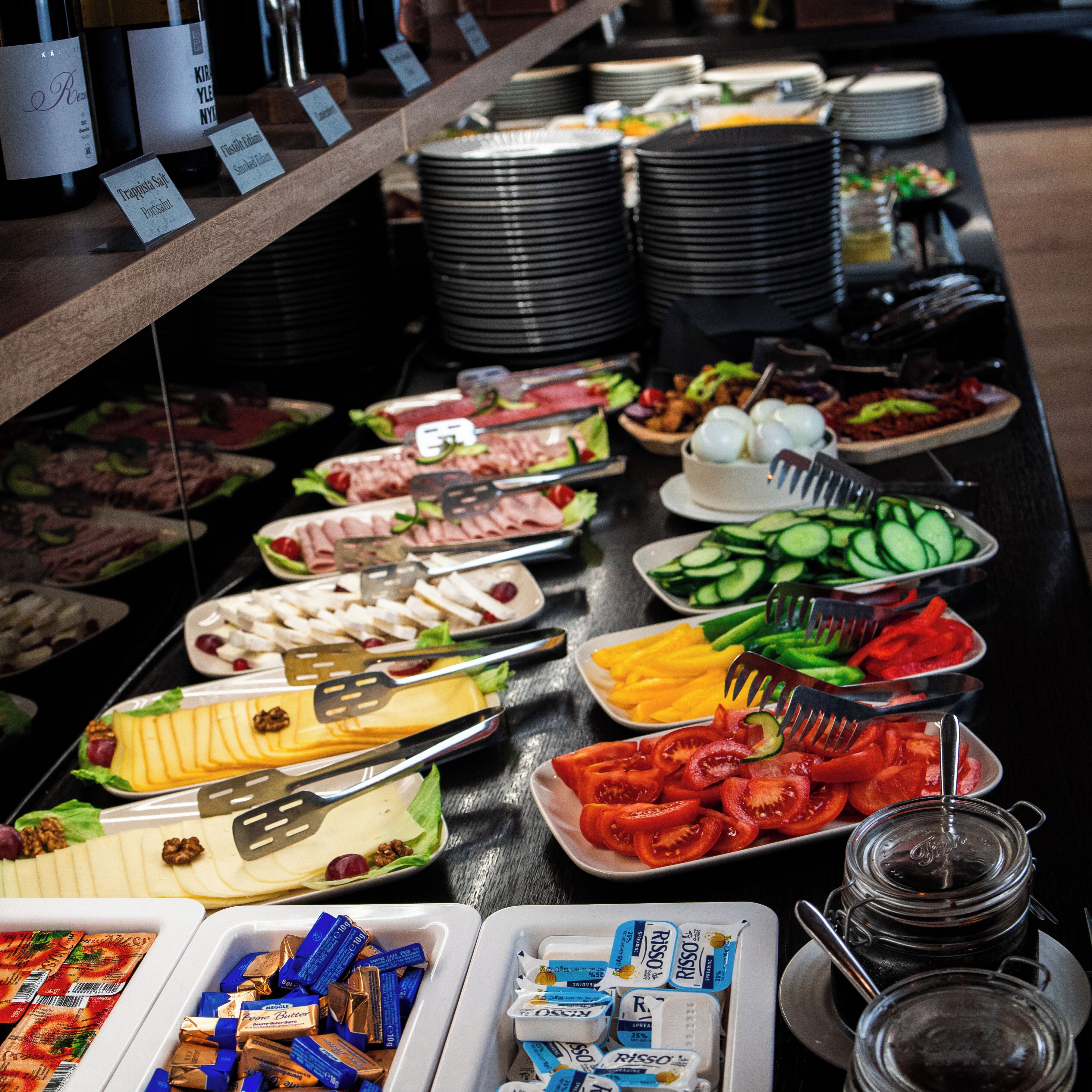 Ein reichhaltiges Buffet mit verschiedenen Speisen, darunter Fleisch, Käse, Obst und Soßen.