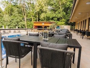 An outdoor dining area with tables and chairs, a pool, and a building with a sign.