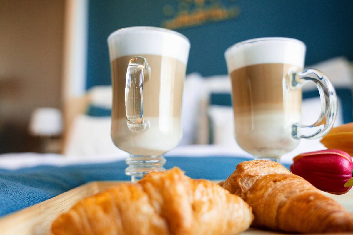 To kaffekopper på et bord med croissanter og tulipaner.