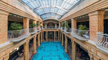 Μια μεγάλη εσωτερική πισίνα με γυάλινη οροφή, που περιβάλλεται από περίτεχους κολώνες και μπαλκόνια με κάγκελα.