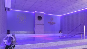 A wellness spa area with a stone wall, a clock, and a statue of a seated figure. - The Hotel Unforgettable - Hotel Tiliana by Homoky Hotels & Spa (Budapest)