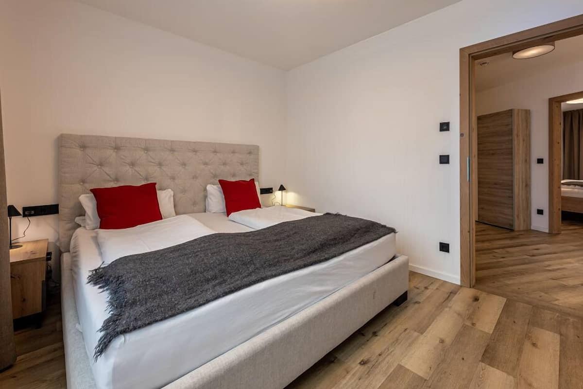 A modern bedroom with a large bed, two bedside tables, and a wooden floor.