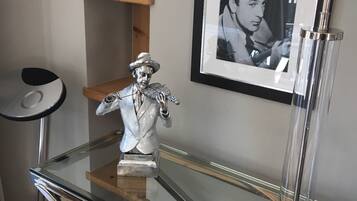 A glass-top desk with a metal sculpture, a framed black-and-white photo, and a modern lamp.