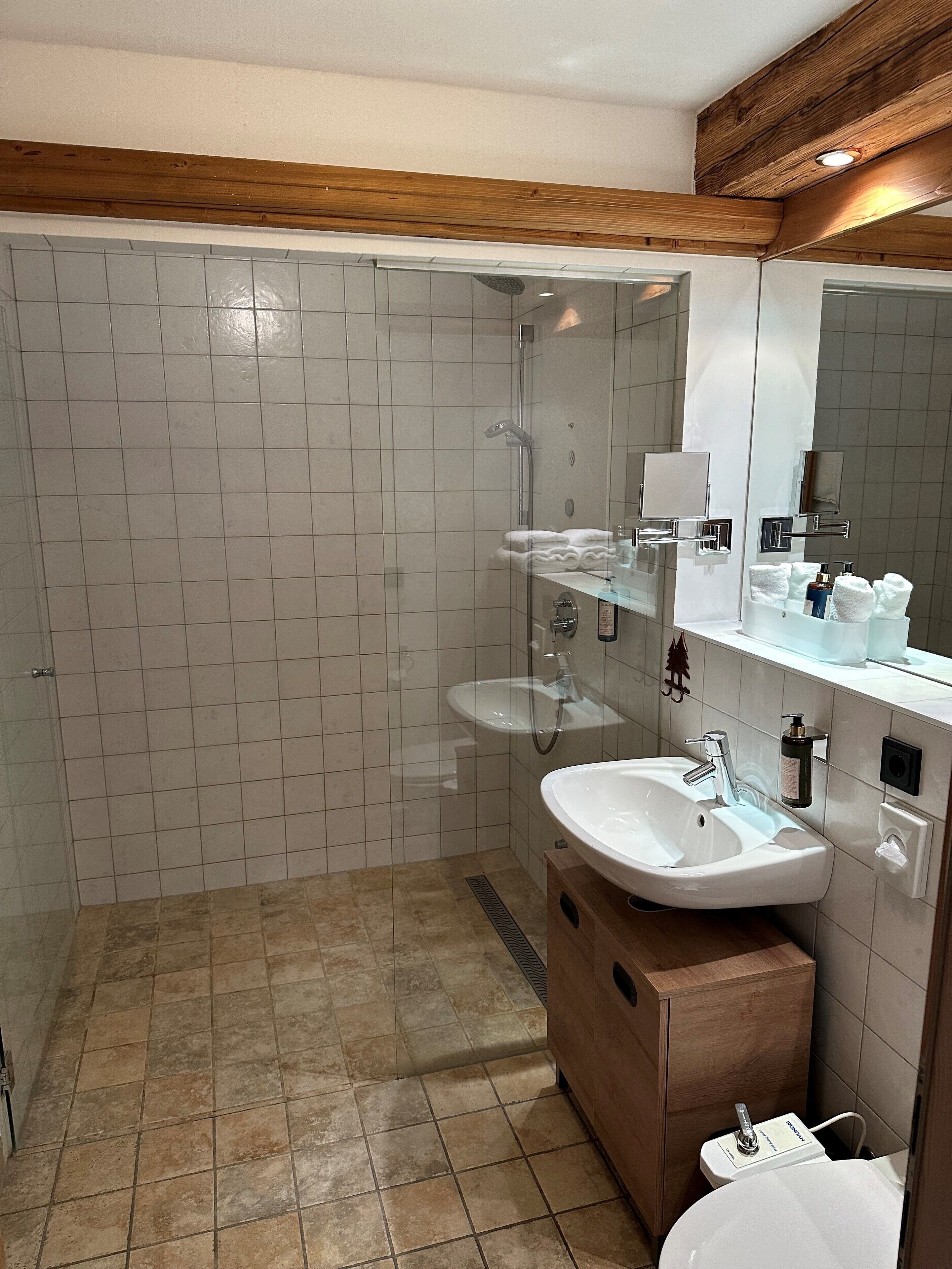 Un baño moderno con cabina de ducha de vidrio, tocador con lavamanos y espejo.