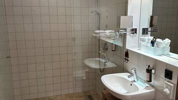Un baño moderno con cabina de ducha de vidrio, tocador con lavamanos y espejo.