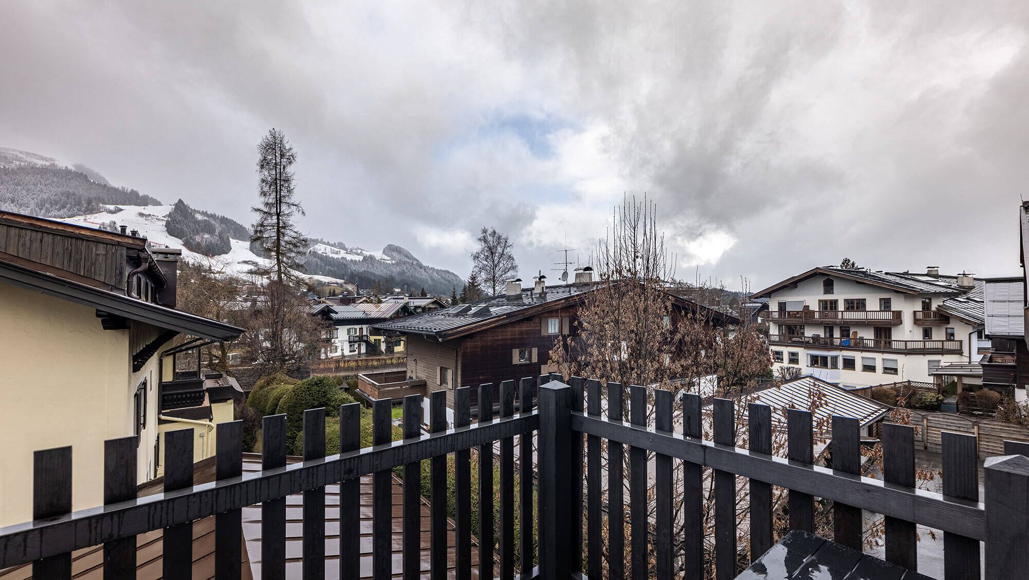 A residential area with traditional wooden houses, a wooden fence, and a mountainous backdrop.