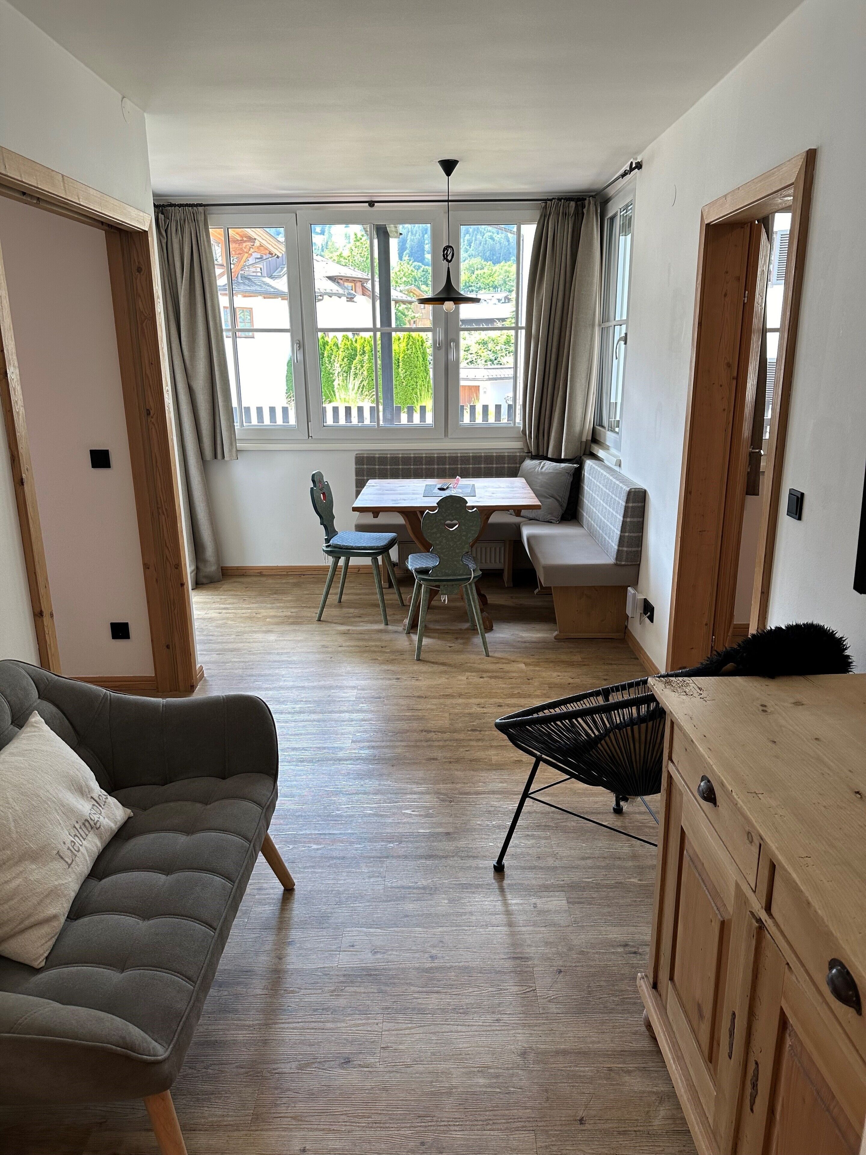Ein gemütliches Wohnzimmer mit einer Couch, einem Esstisch mit Stühlen und einer Holzkommode.