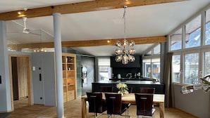 Una cocina moderna con una isla central, vigas de madera y ventanas amplias.