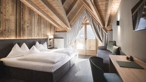 A modern bedroom with a large bed, a desk, and a chair. - Alpenhof (Ultimo)