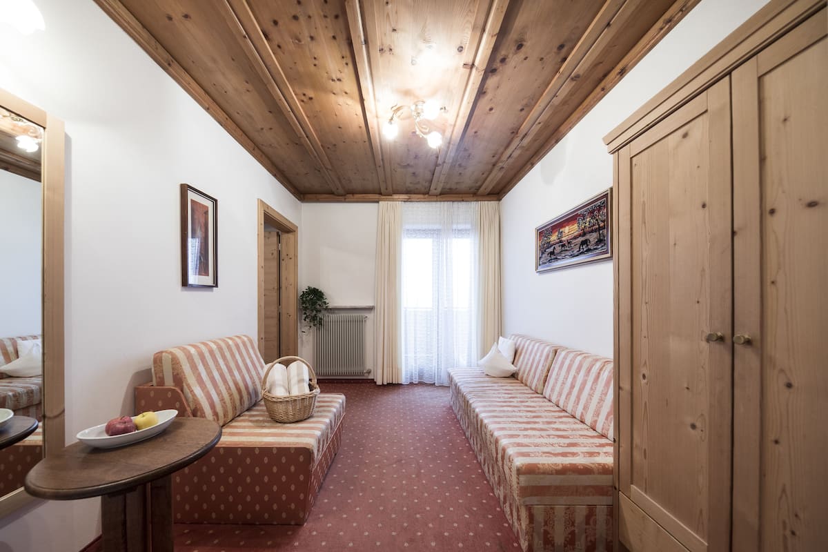 Una habitación acogedora con techo de madera, un sofá, una mesita con un plato de fruta y un radiador.