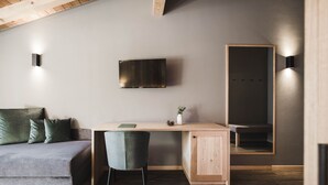 A modern bedroom with a wooden desk, a grey sofa, and a large mirror. - Alpenhof (Ultimo)