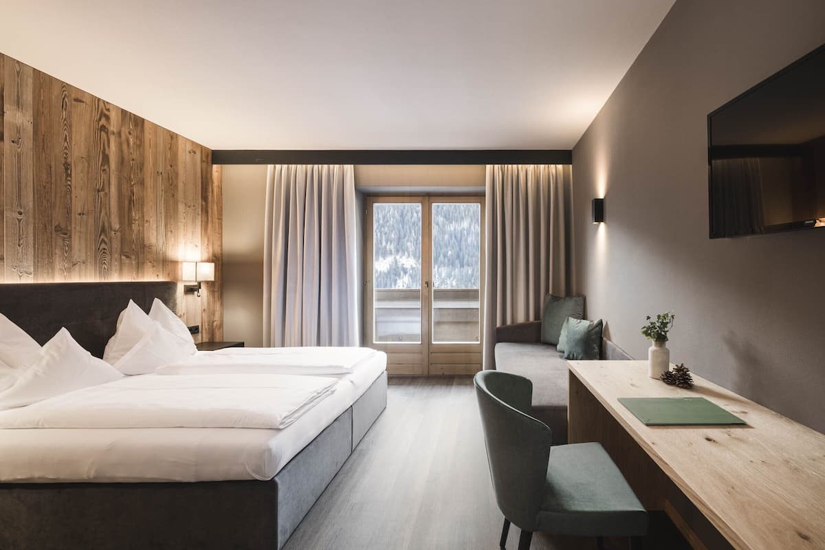 Una habitación de hotel moderna con una cama grande, un escritorio y vistas a un paisaje nevado a través de la ventana.