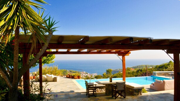 A poolside area with a pergola, outdoor seating, and a view of the sea. - Paparouna (Alonissos)