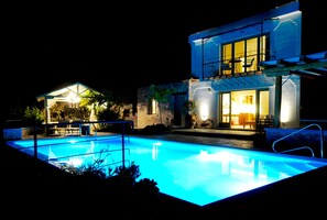 Una casa moderna con piscina, un patio cubierto y un comedor.