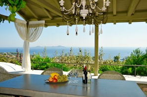 A table with a bottle of wine, glasses, and a fruit bowl. - Paparouna (Alonissos)