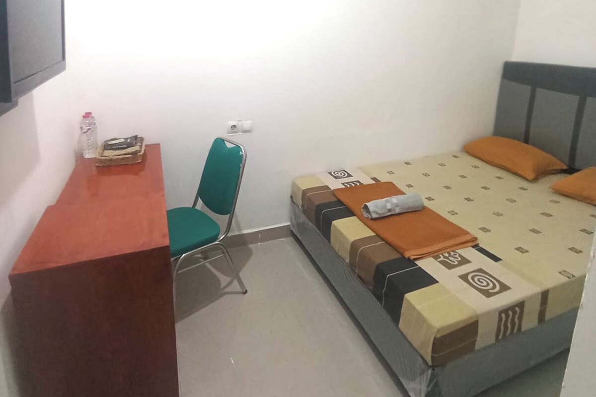 Una habitación pequeña y sencilla con una cama, un escritorio y una silla.