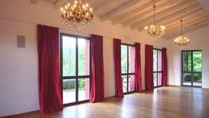 Une pièce spacieuse avec de grandes fenêtres, un plancher en bois et deux lustres.